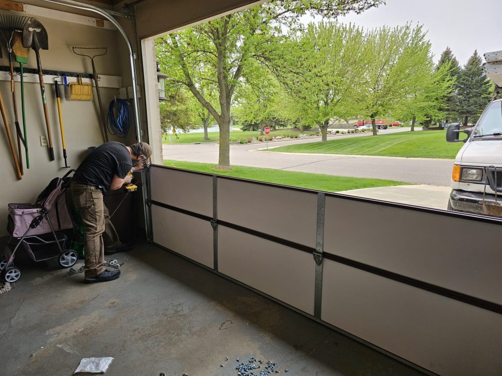 David Tuito installing garage door panels on site in Minnesota - real work photo David's Urgent Garage Door