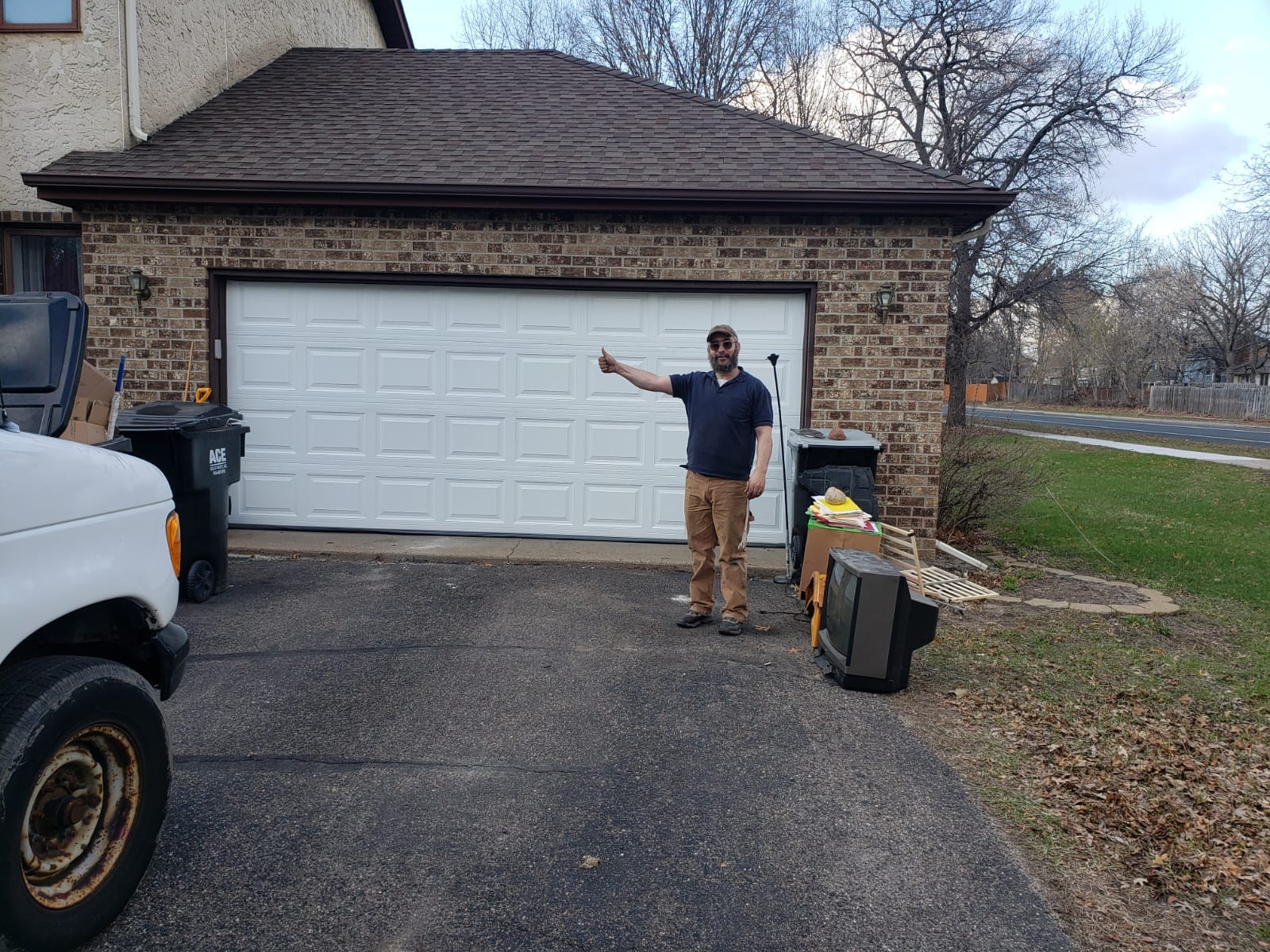 David Tuito giving thumbs up after completing garage door installation on brick home Minnesota