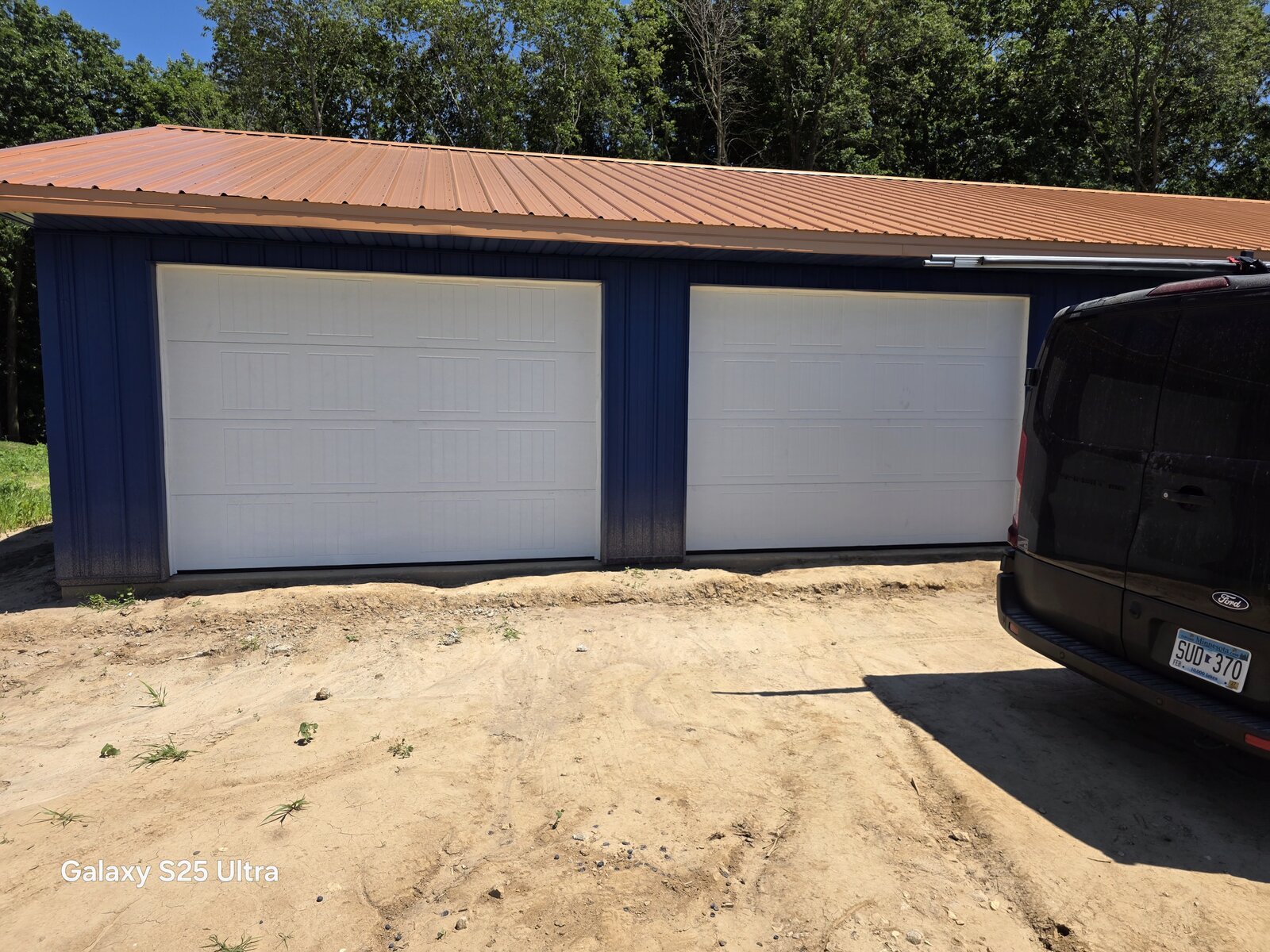 Two new white garage doors on a finished pole barn