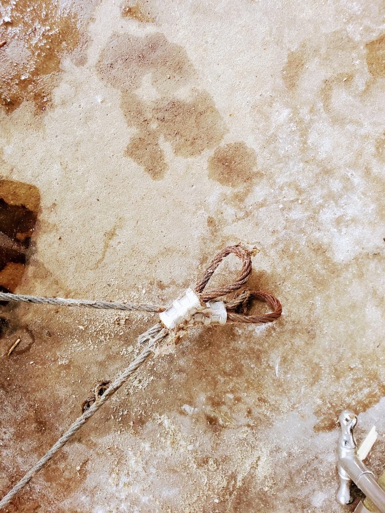 Broken garage door cable end with rusted clip after snapping at the bottom bracket