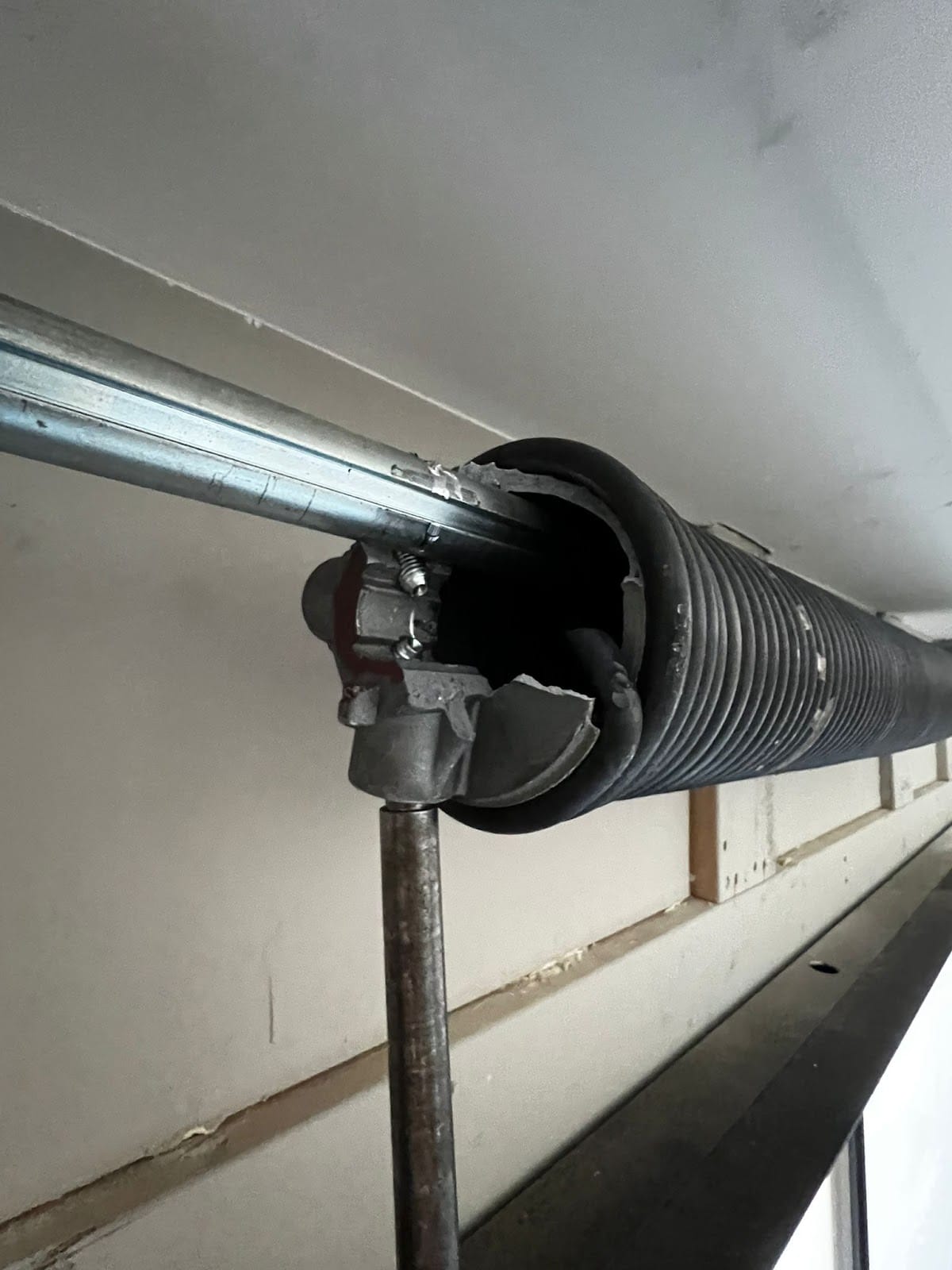 Broken garage door torsion spring with the visible gap in the coil - the typical fatigue failure after 10,000 cycles