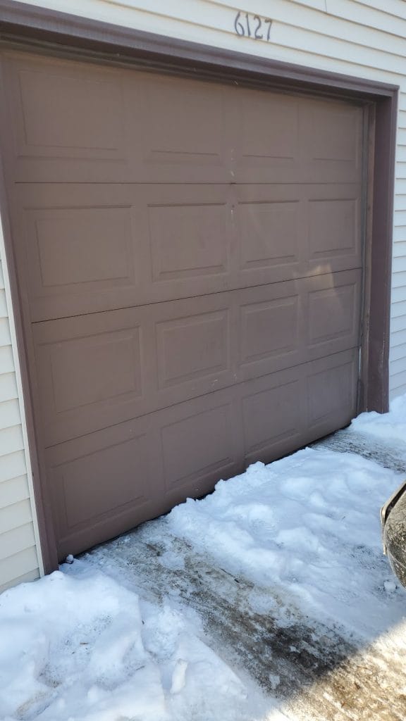 Brown raised-panel garage door repaired in the middle of a Minnesota winter