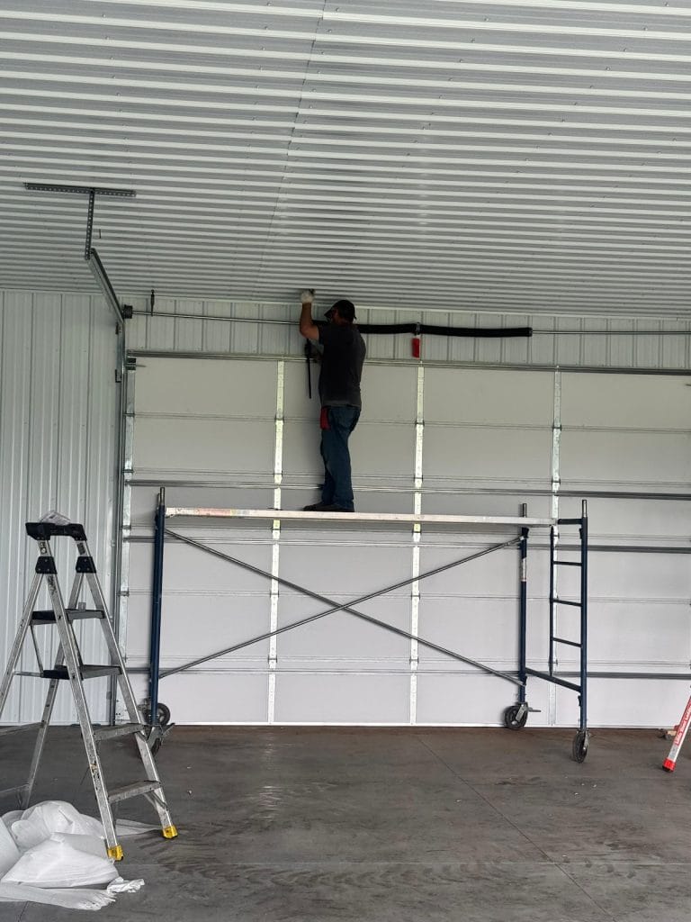David installing a commercial sectional garage door from a scaffold