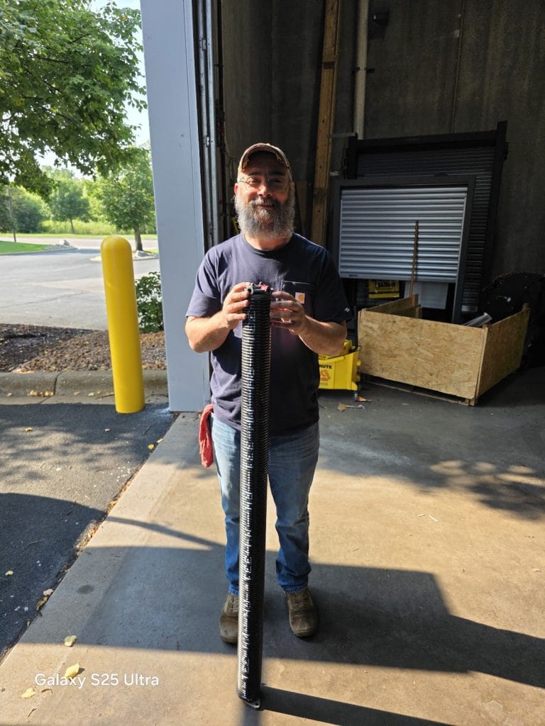 David Tuito holding a new torsion spring before a garage door repair