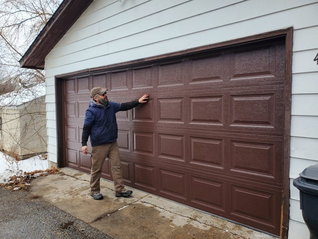 David beside a newly installed brown raised-panel garage door