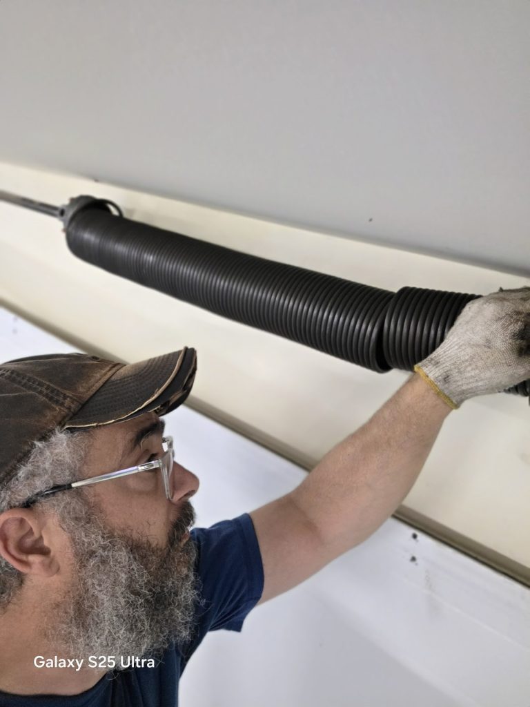 Close-up of David winding a new torsion spring on a garage door, serving Vadnais Heights, MN
