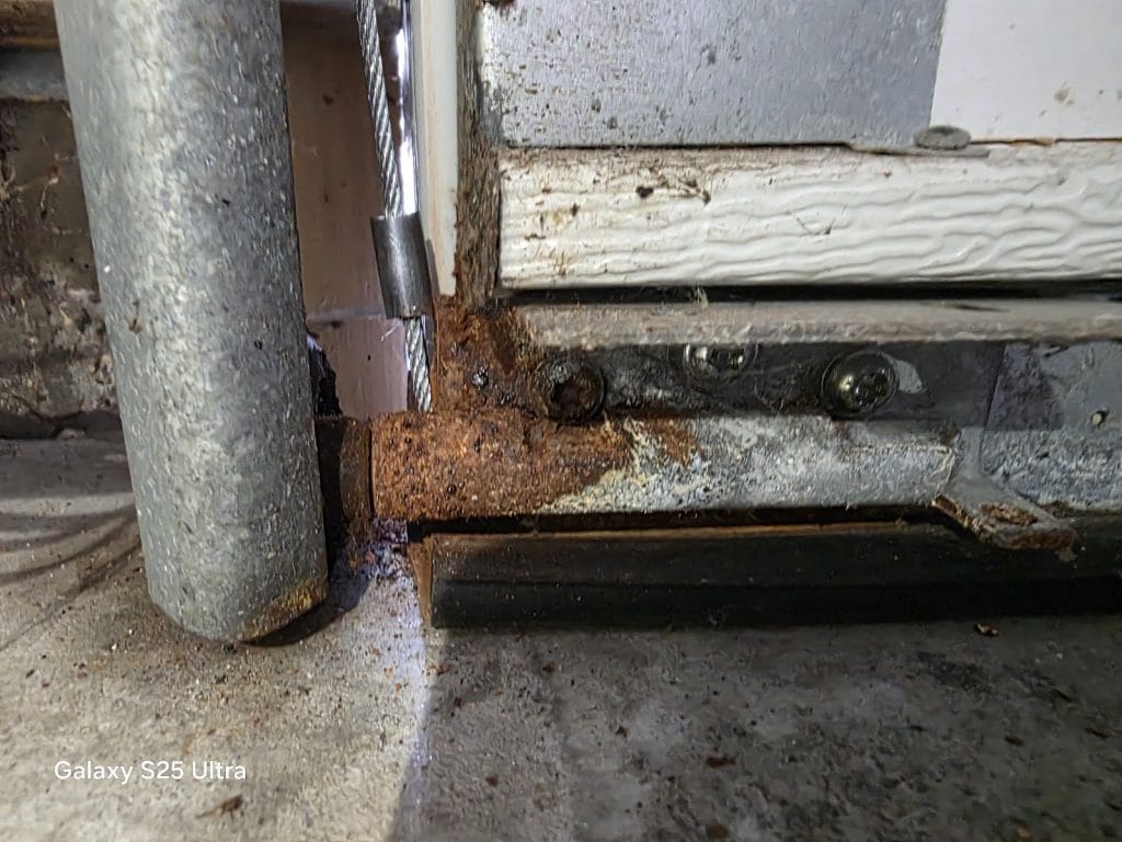 Rusted garage door bottom bracket and cable attachment corroded by road salt