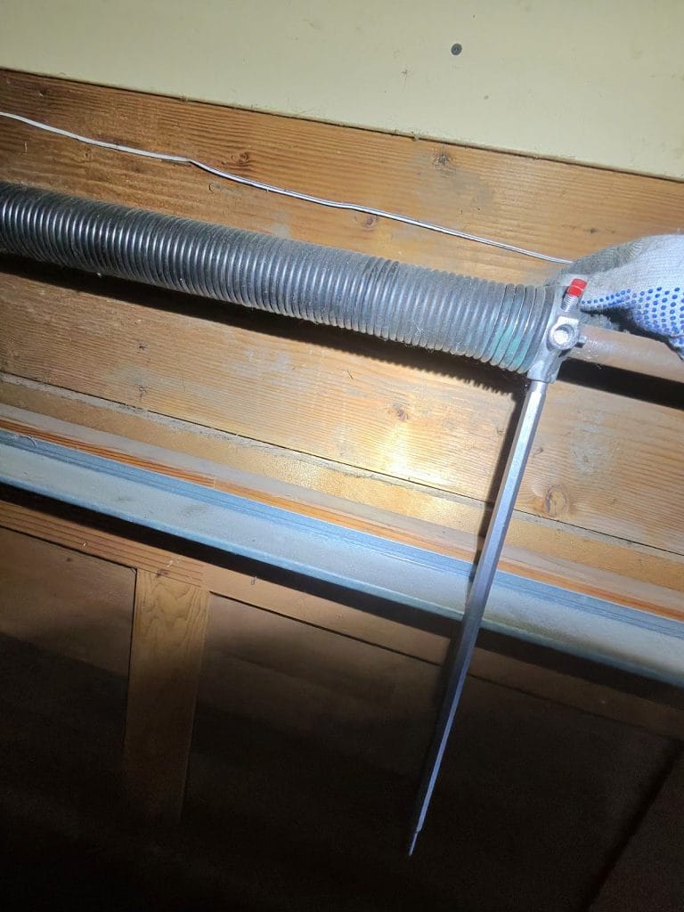 Torsion spring being adjusted with a winding bar during a garage door spring repair, Minneapolis-St. Paul