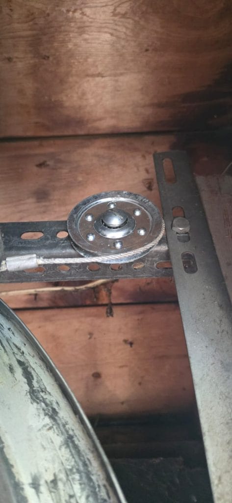 Worn extension-spring pulley with frayed garage door cable strands