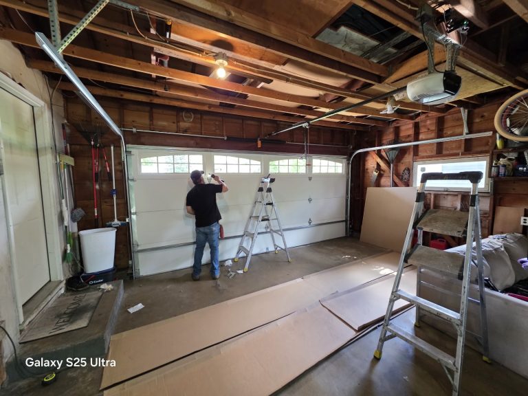David installing a new white garage door with windows, new sections laid out on the floor