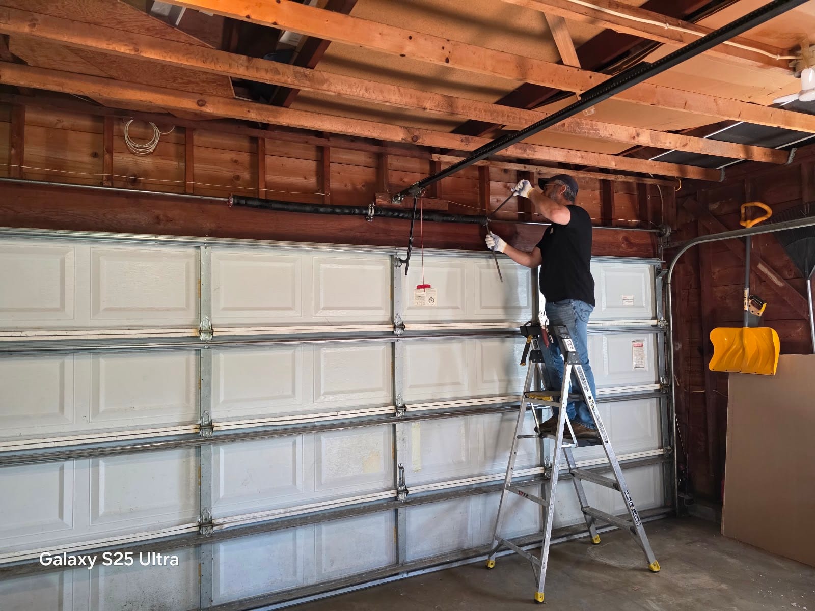 David on a ladder installing hardware above a white garage door