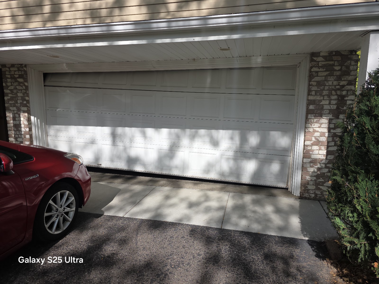 Garage door open on a brick garage with the car inside after repair