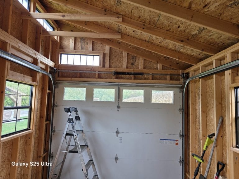 Newly installed white garage door with a row of windows, inside a wood-framed garage