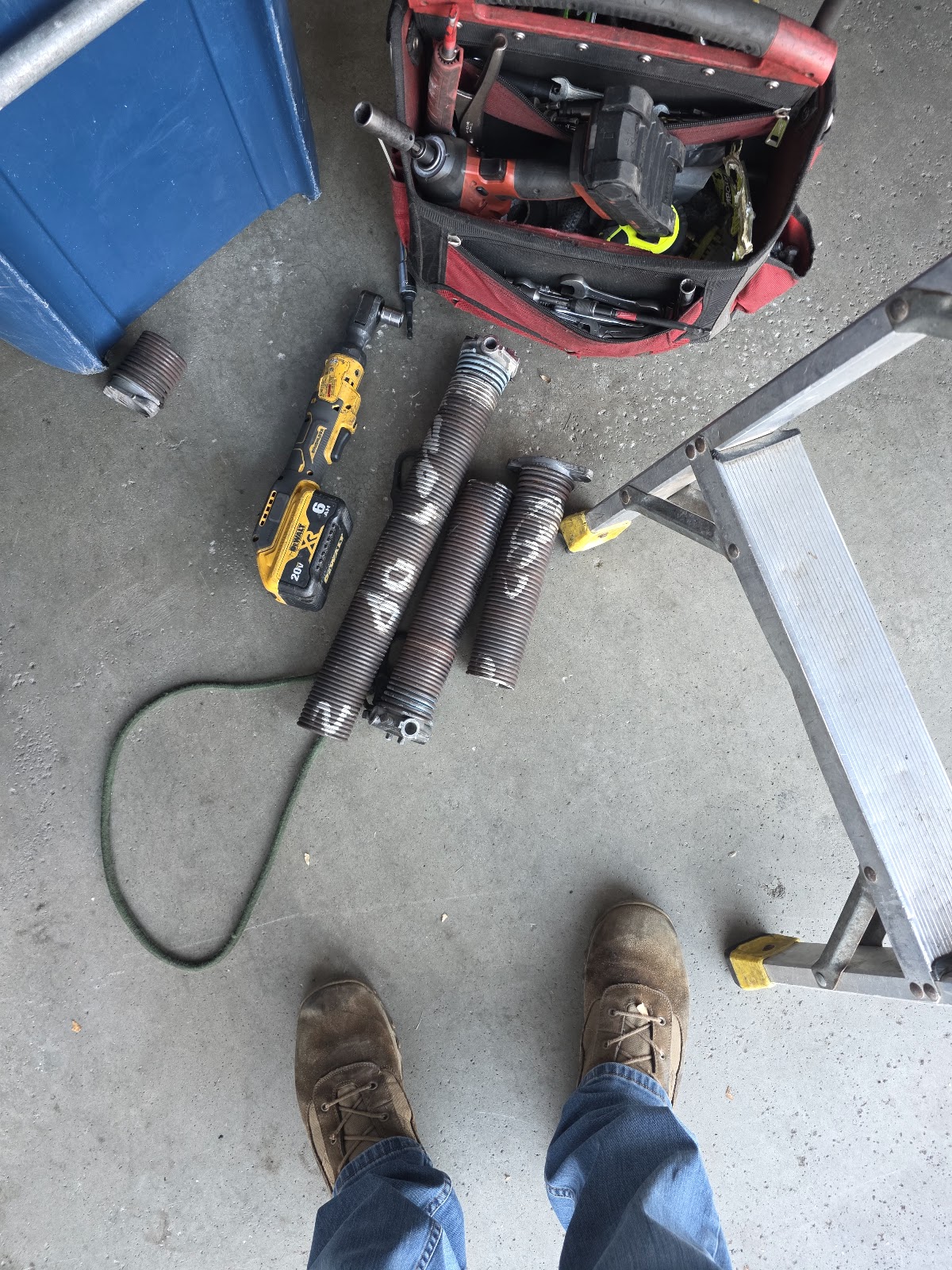 Old broken torsion springs and tools on the driveway after replacement