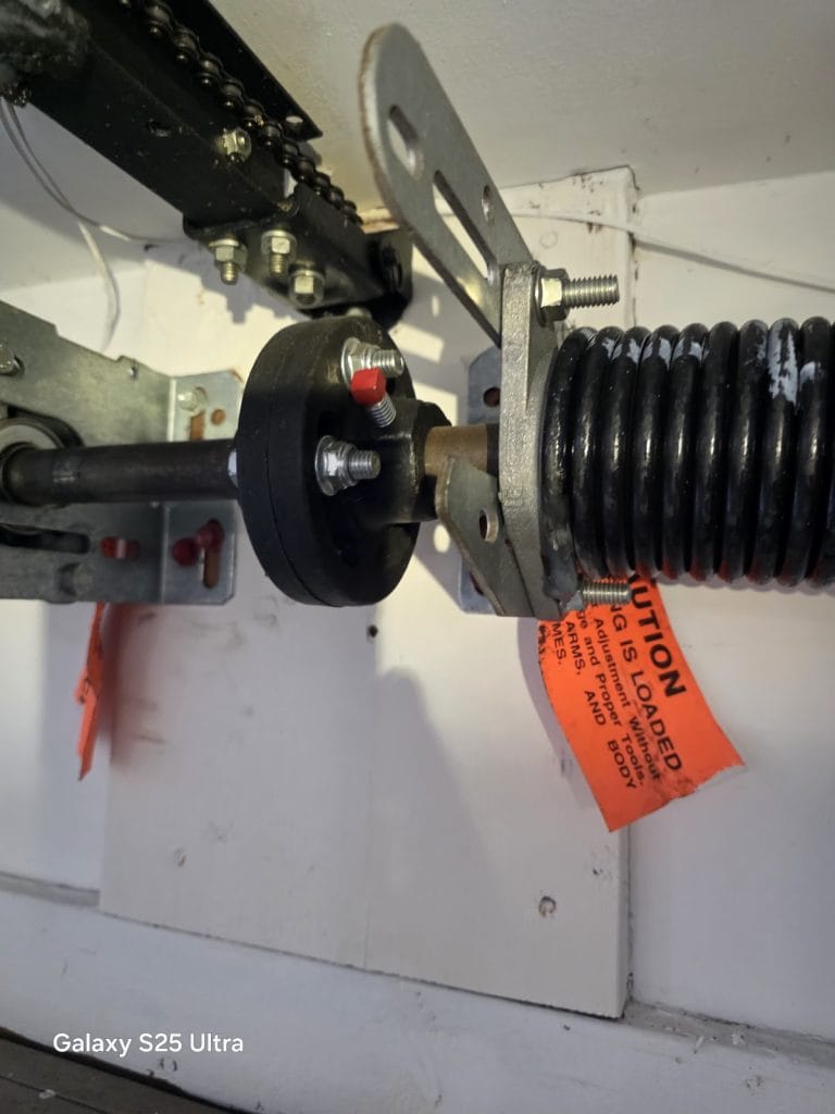 New torsion spring with winding cone and caution tag on the center bearing bracket after a spring replacement, Minnesota